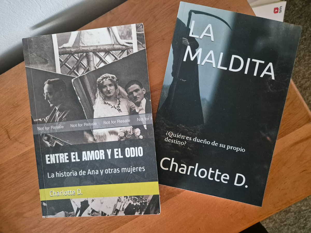 Dos libros de Charlotte D. dispuestos sobre una mesa: “Entre el amor y el odio” y “La maldita”, mostrando sus portadas en un contexto doméstico.