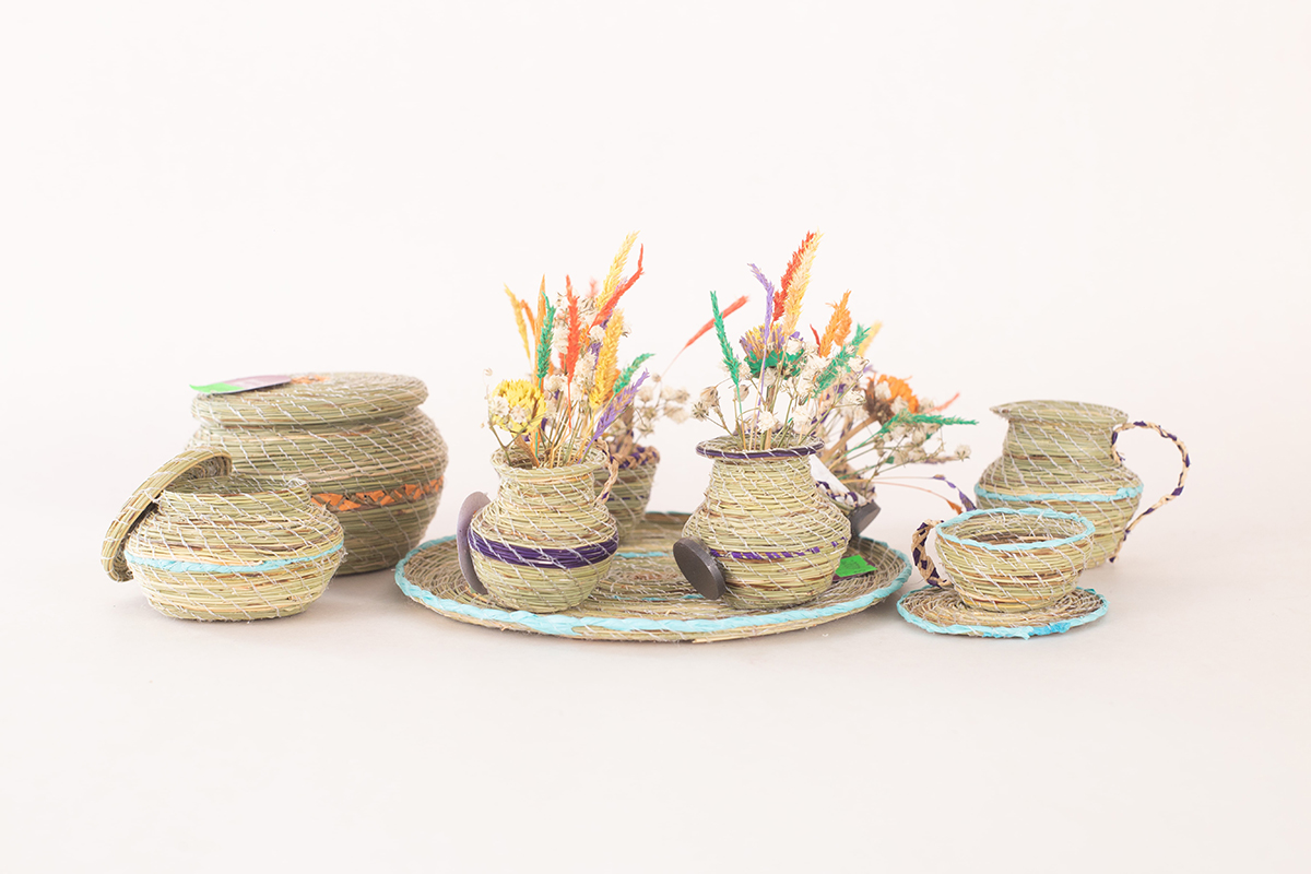 Canastos y posavasos circulares tejidos en fibra vegetal natural, dispuestos en conjunto sobre fondo blanco, con detalles de color en los bordes.